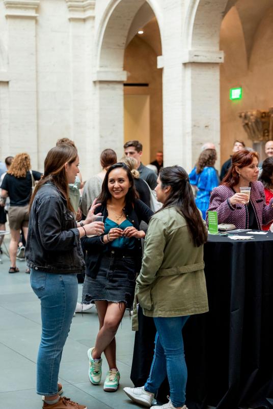 A courtyard filled with visitors chatting over drinks at high-top tables.