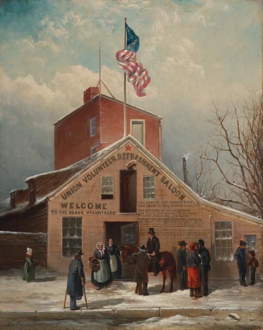 A group of men and women are gathered in front of a peak-roof building with an American flag on top.
