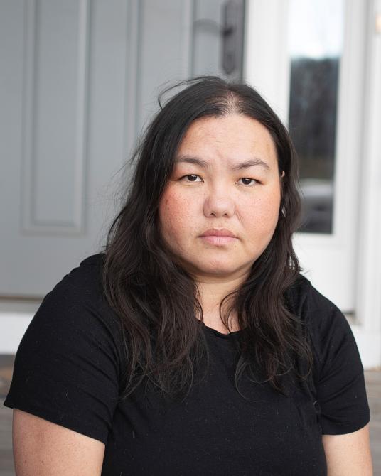 A color photograph of a woman staring directly at the camera.