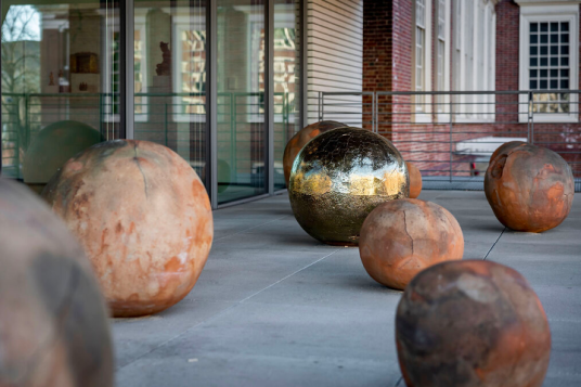 Several terracotta spheres and one gold sphere installed on an enclosed terrace.