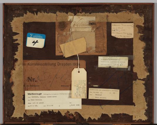 Various labels, stickers, and a tag are attached to a wooden surface.