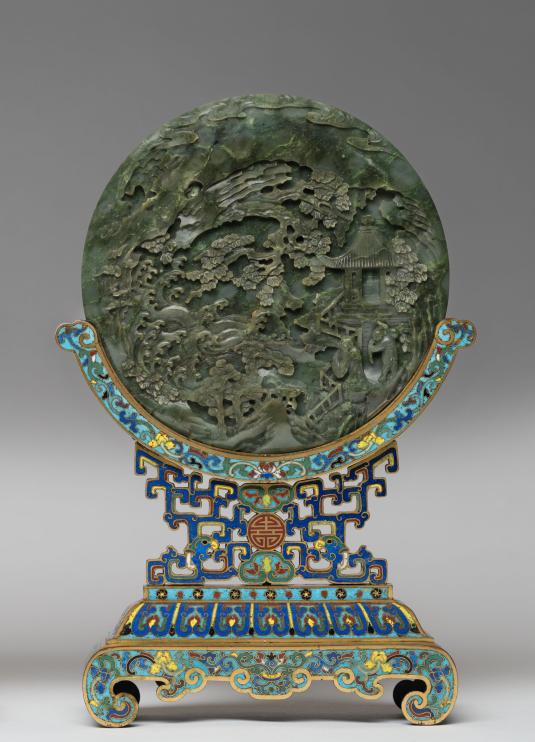 A green jade disk mounted on a colorful metal stand.