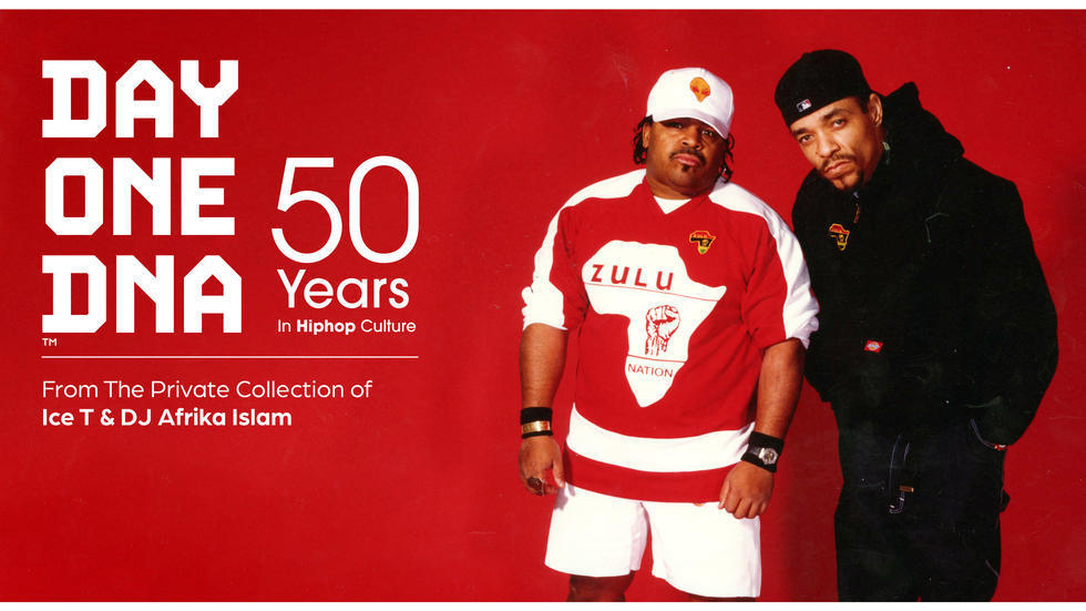 Afrika Islam and Ice T stand together looking seriously into the camera. Afrika is wearing a white baseball cap with an alien on it and a sweatshirt for Zulu Nation with a raised fist in the center of Africa. Ice T wears a black sweatshirt for Zulu Nation