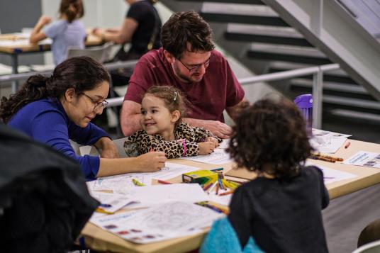 A family happily draws together at a coloring station.
