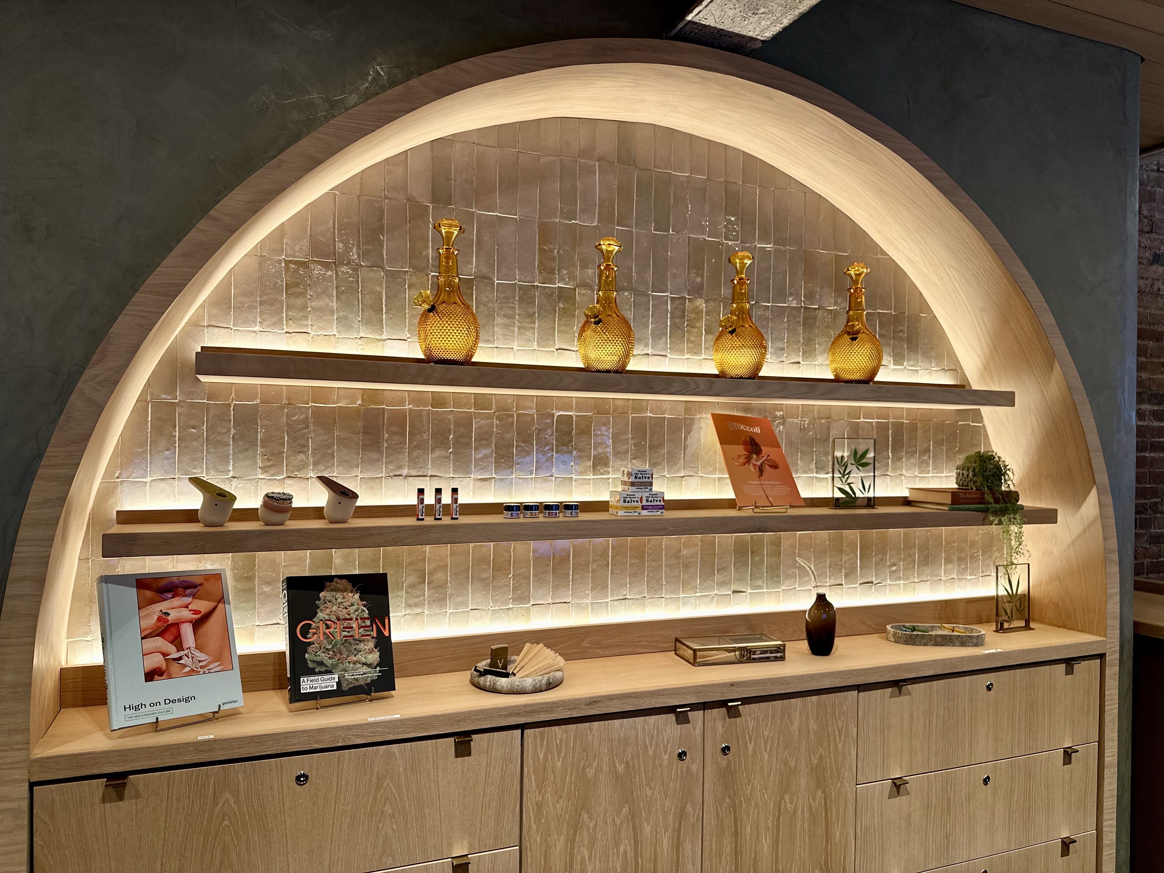 A shelving unit showing orange-tinted bongs, clay pipes and books behind the counter at Yamba Boutique in Cambridge. 