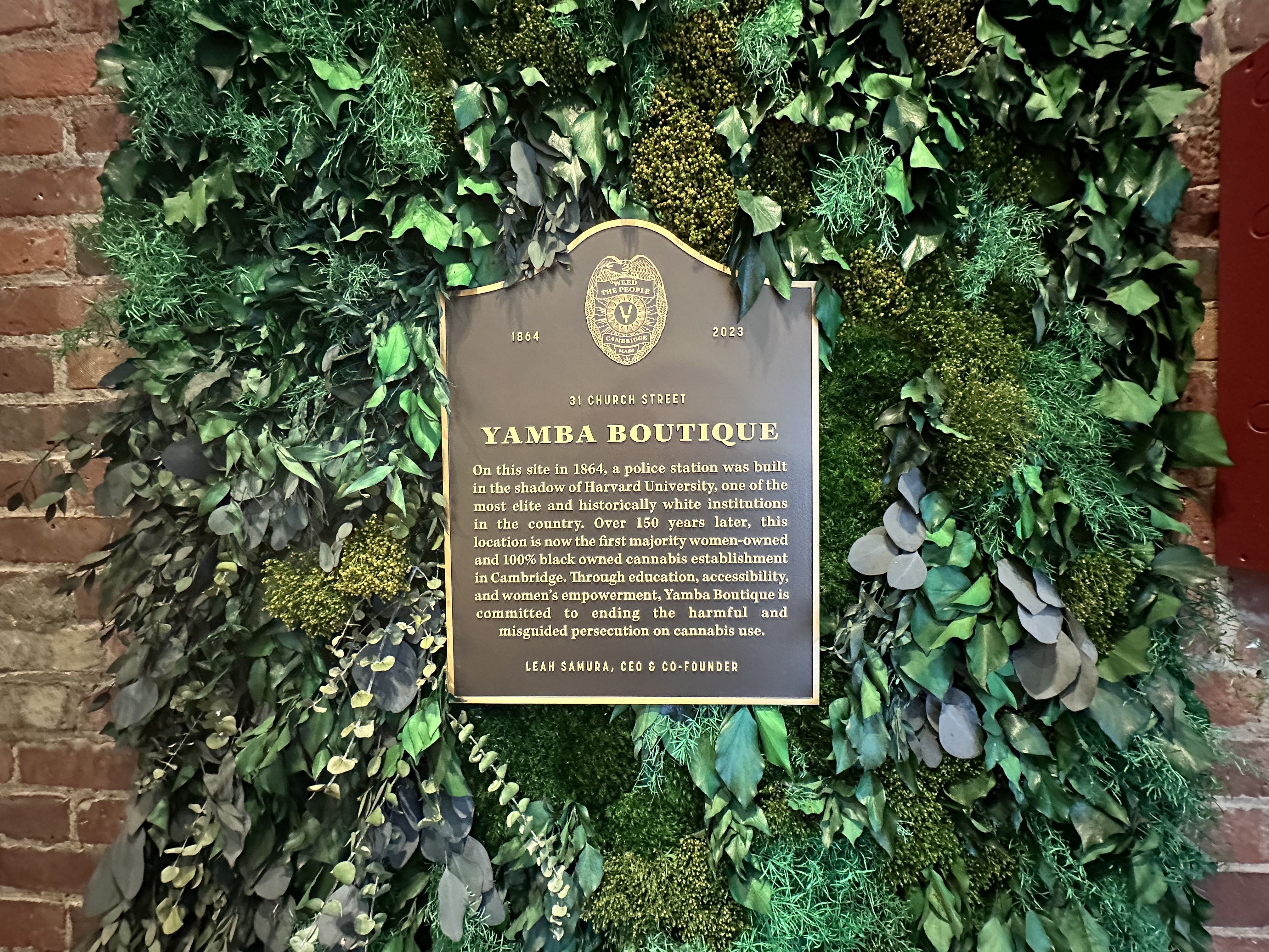 A plaque at the entry of Yamba Boutique says: "On this site in 1864, a police station was built in the shadow of Harvard Univeristy, one of the most elite and historically white institutions in the country. Over 150 years later, this location is now the first majority woman-owned and 100% black owned cannabis establishment in Cambridge. Through education, accessibility and women's empowerment, Yamba Boutique is committed to ending the harmful and misguided persecution on cannabis use."" 