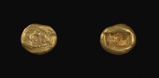 Two irregular gold coins against a black background.