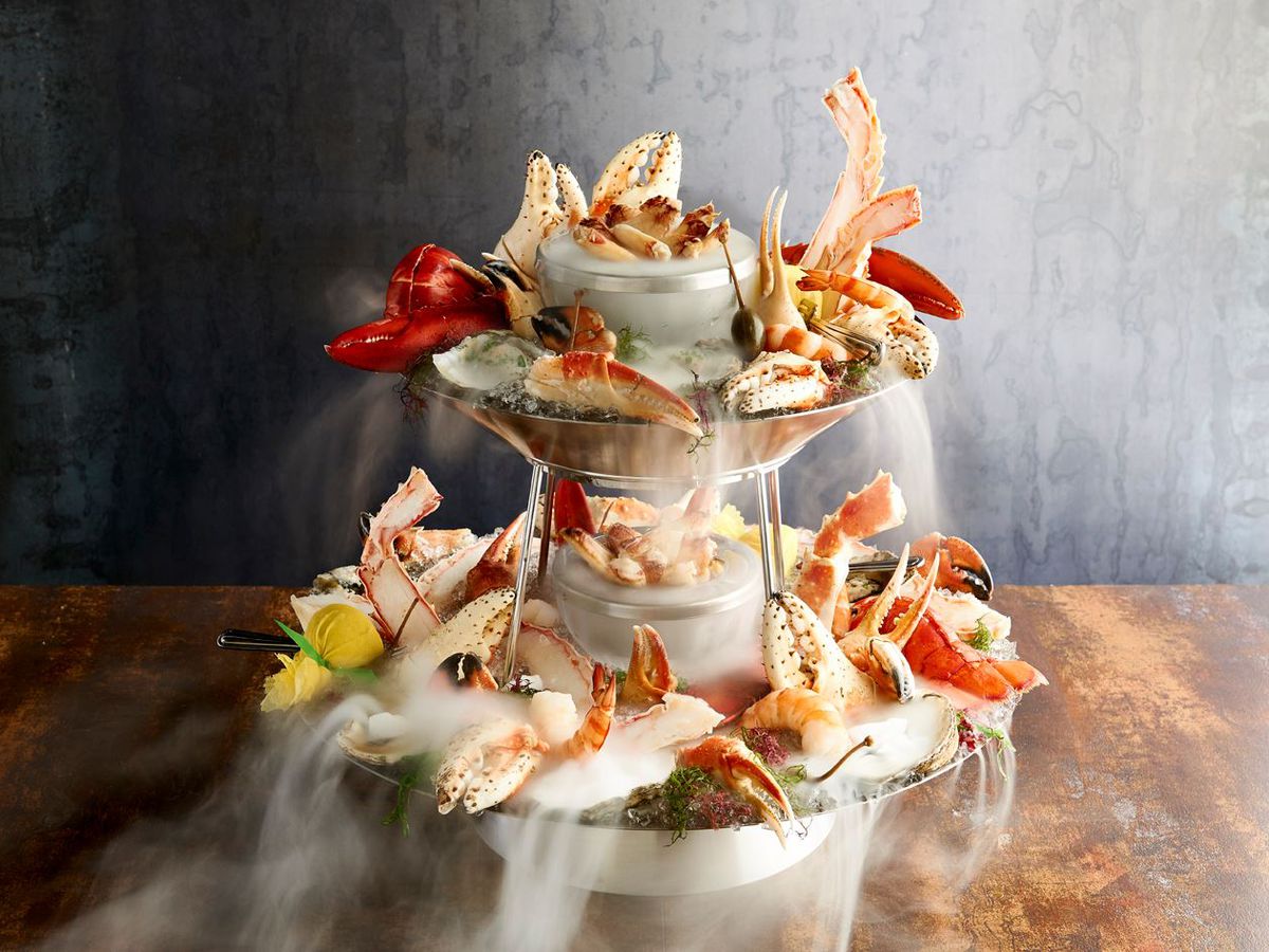 Glamour shot of a multi-tier seafood tower, garnished with plenty of crab claws and dry ice
